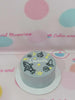 One-tier grey space cake with hand-piped rocket, UFO, planets, yellow stars, and '1 month' text in buttercream.