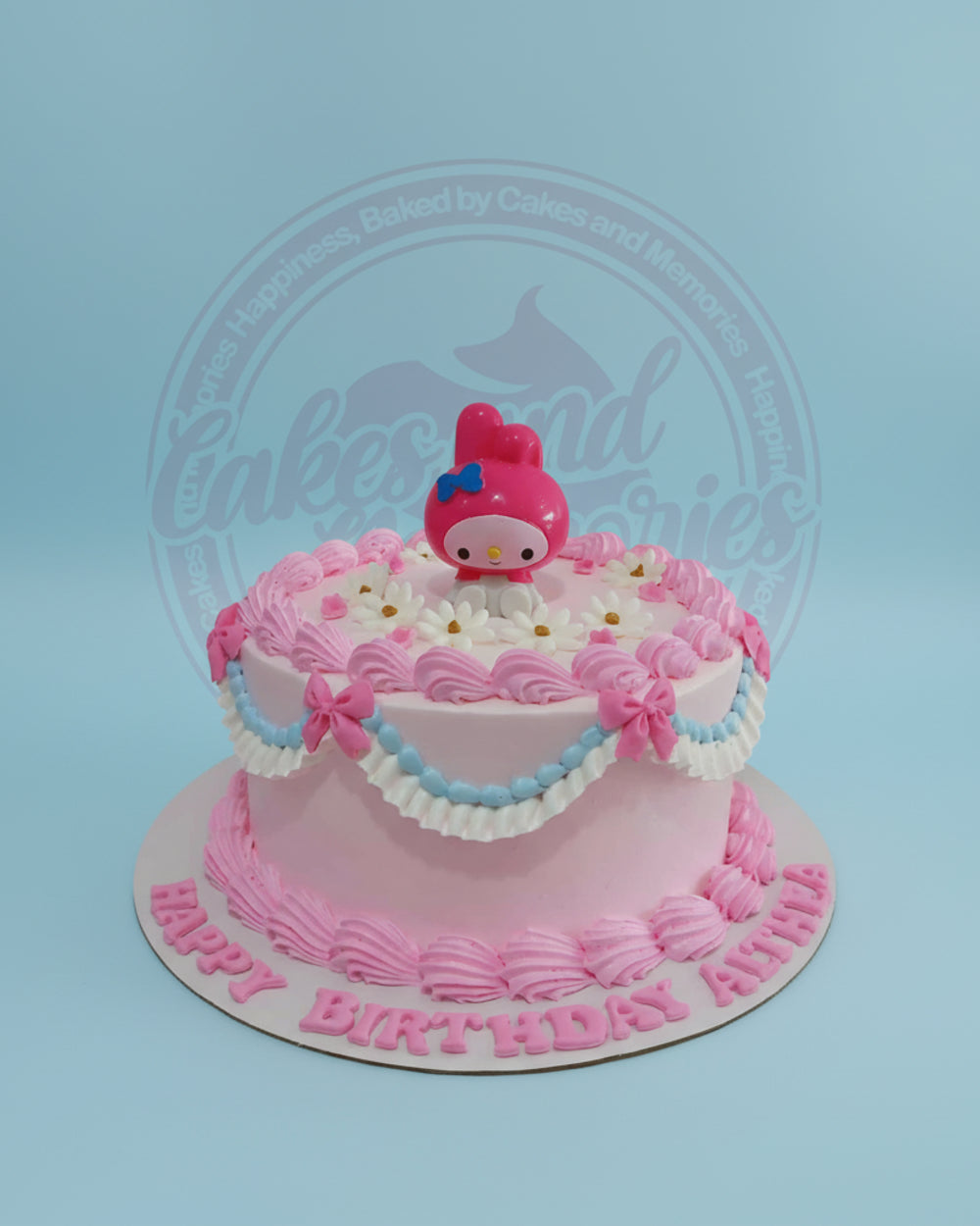 One-tier My Melody birthday cake with pink buttercream, white daisies, blue/white ruffles, and 'Happy Birthday Aliha' lettering.