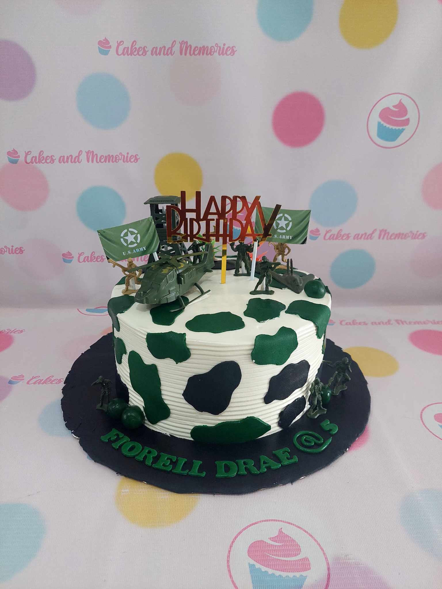 One-tier military-themed birthday cake with green and black camouflage, army figurines, and 'Fiorell Drae @ 5' text.