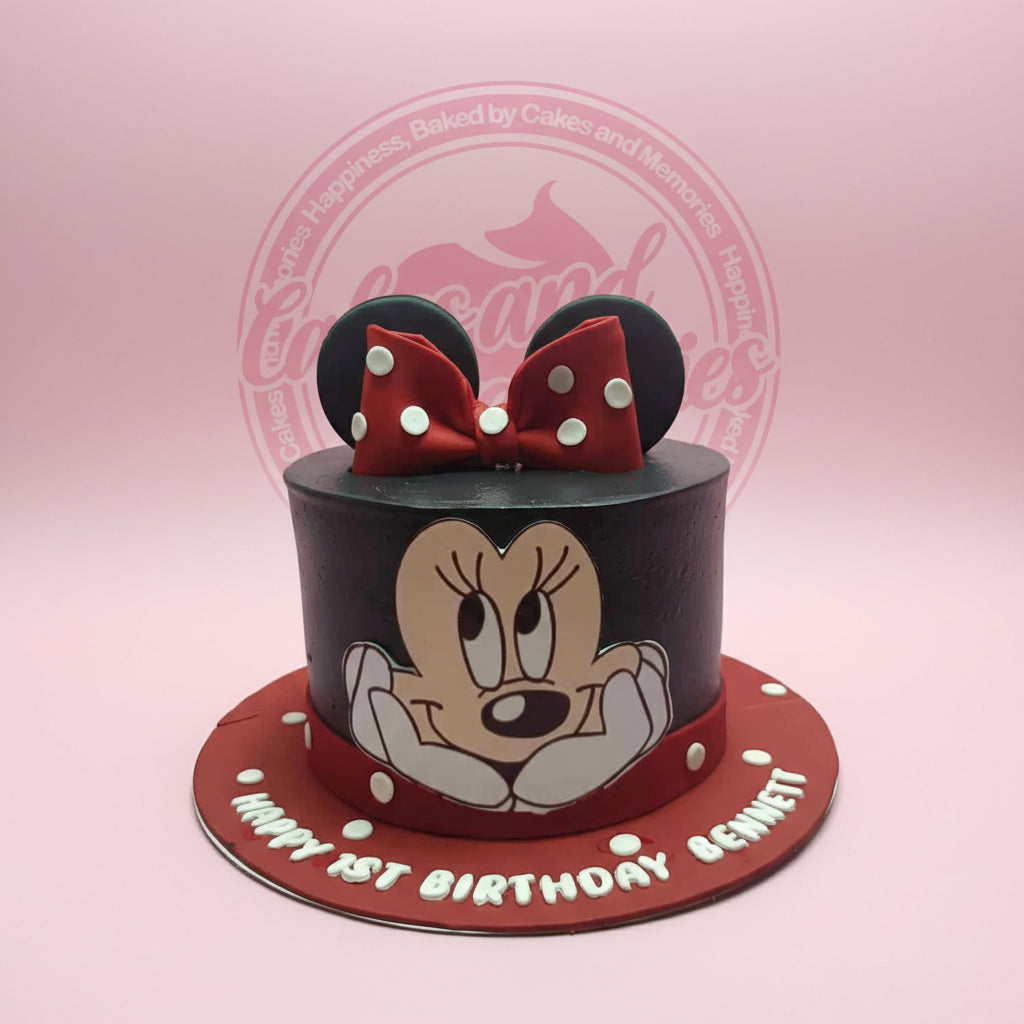 1-tier Minnie Mouse birthday cake with black buttercream, red polka dots, fondant ears and bow, and 'Happy 1st Birthday Bennett' text.