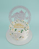One-tier birthday cake with white buttercream, delicate white flowers, green leaves, gold pearls, and 'happy birthday Mama Emy!'