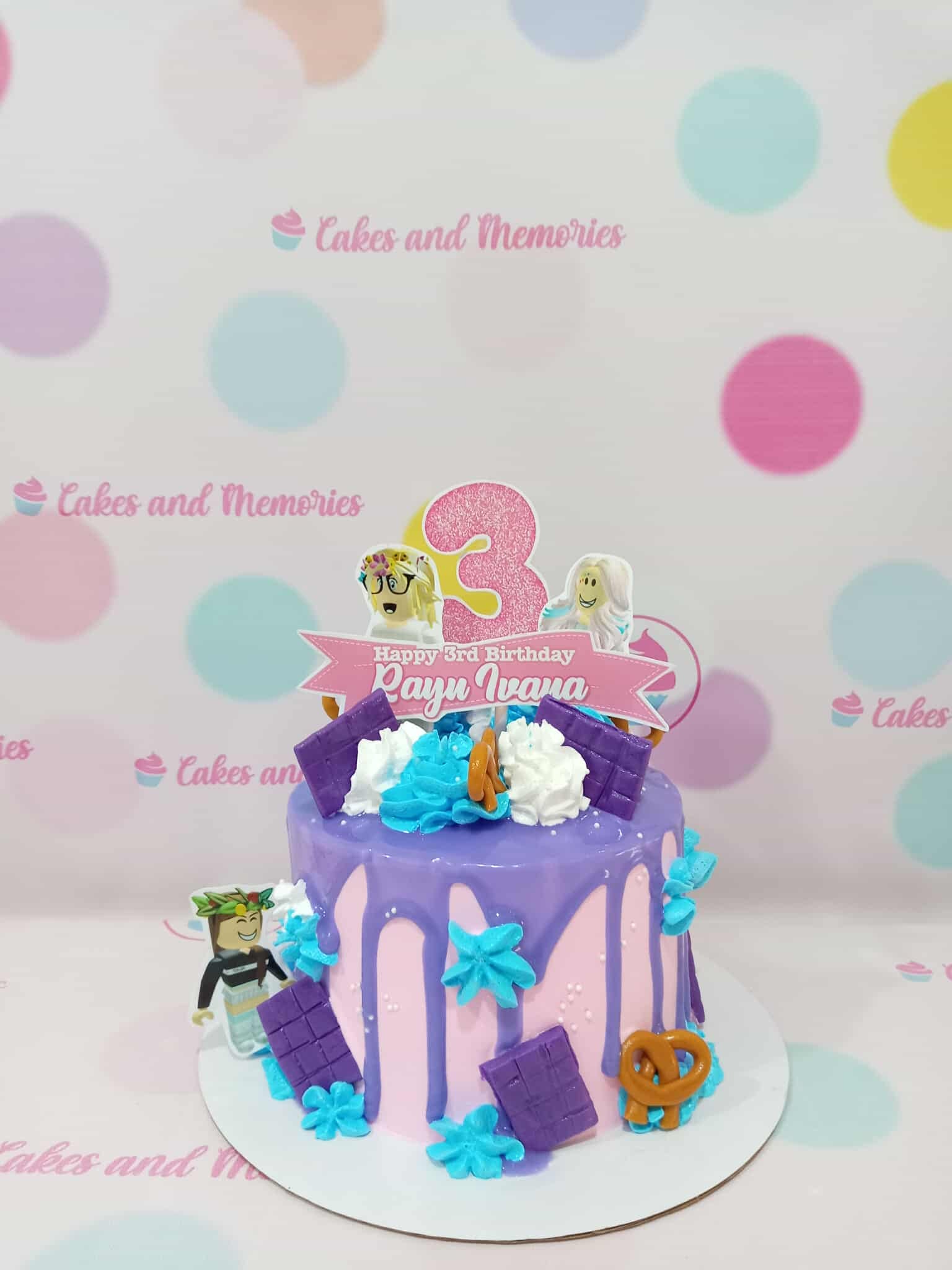 One-tier Roblox birthday cake with pink base, purple drip, "Happy 3rd Birthday Rayu Ivana" topper, and character cutouts.