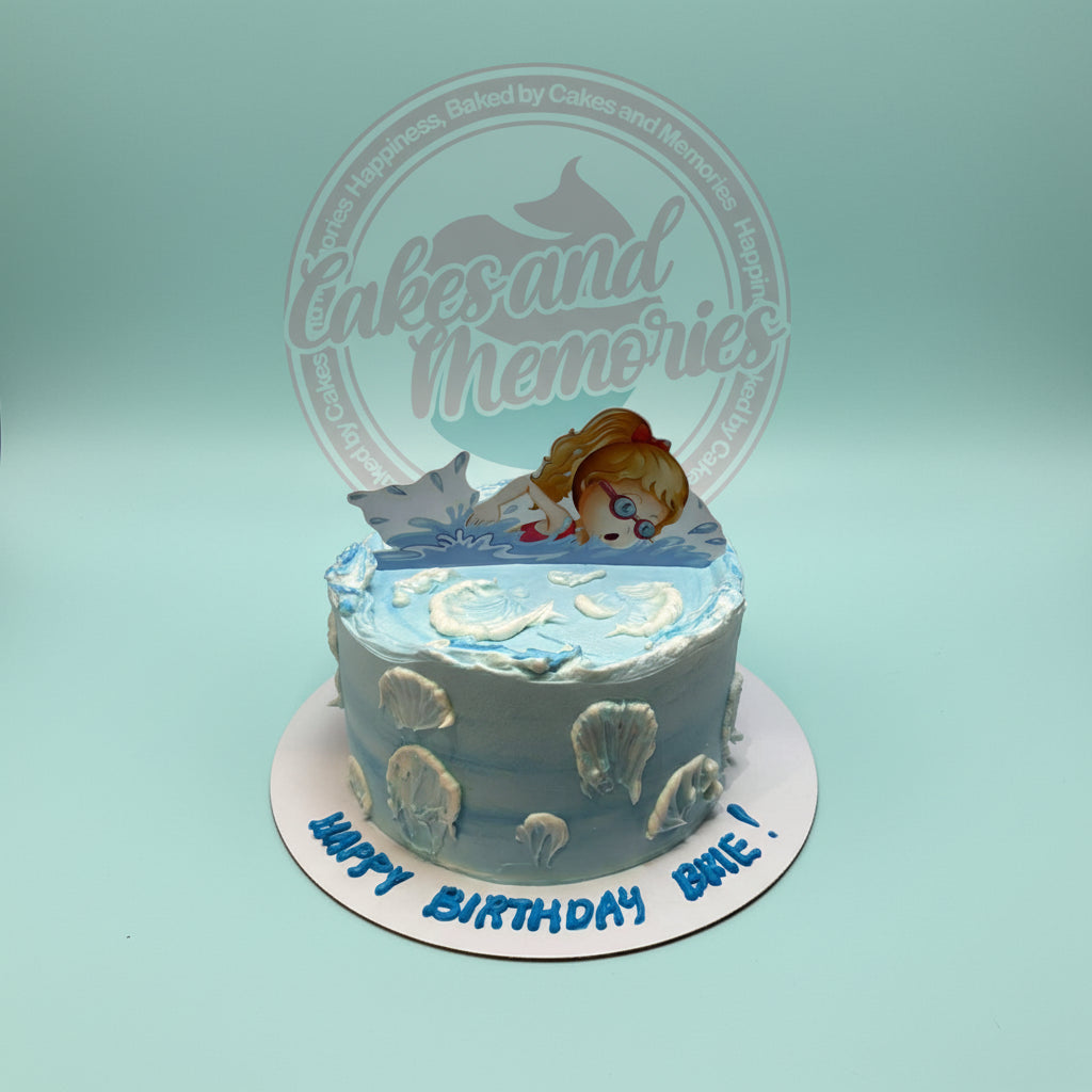 One-tier pool-themed buttercream cake with a swimmer girl topper, white shell details, and "HAPPY BIRTHDAY EMIE!" text.