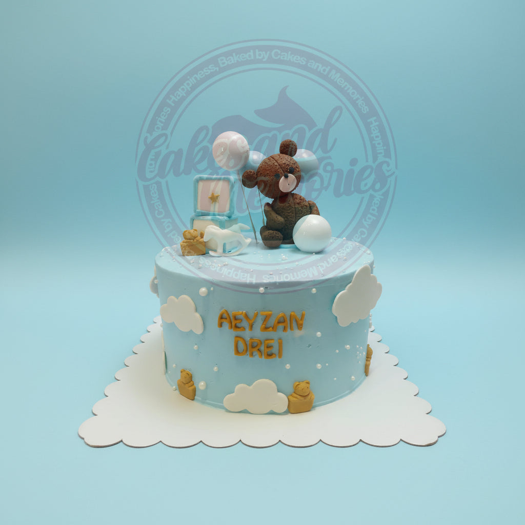 One-tier baby boy cake with teddy bear, clouds, balloons, rocking horse, and blocks in blue and white, with 'AEYZAN DREI' text.