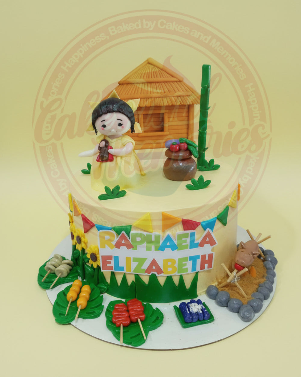 One-tier birthday cake with Filipino heritage theme, featuring a girl, nipa hut, carabao, and Raphaela Elizabeth banner in yellow and green.