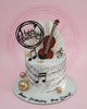 Round music birthday cake with white buttercream, musical notes print, violin topper, gold spheres, and 'Happy Birthday Bro. David!' text.