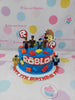 One-tier blue Roblox birthday cake with characters, building blocks, sprinkles, and 'Happy 7th Birthday Primo' lettering.