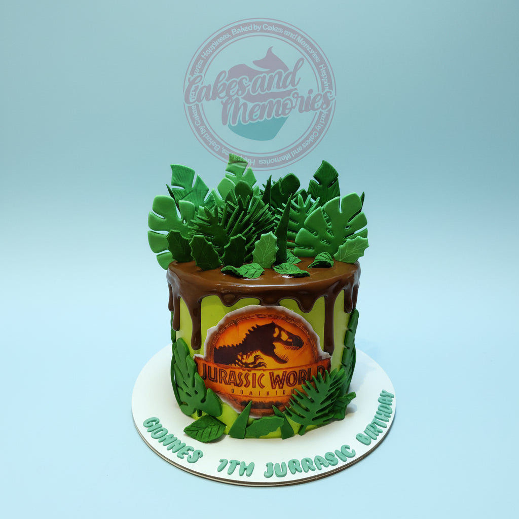 One-tier birthday cake with Jurassic World: Dominion theme, featuring lime green icing, chocolate drip, green leaves, and "Gionnes 7th" text.