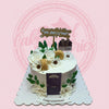 One-tier housewarming cake with white roses, daisies, green leaves, gold macarons, purple door, and 'Congratulations' topper.