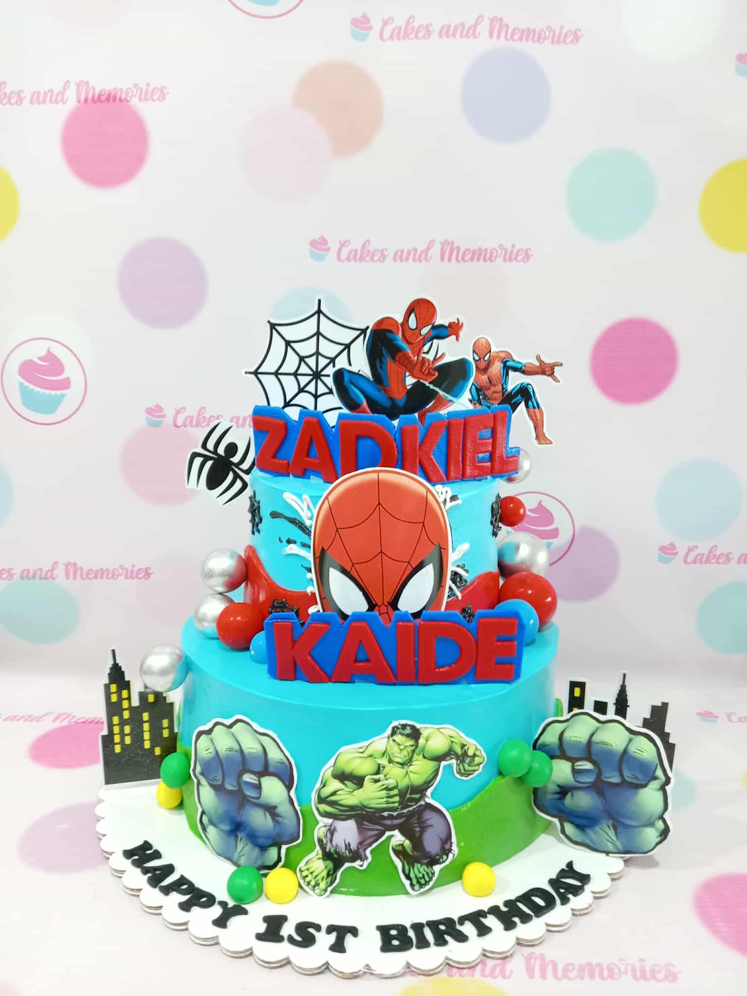 Two-tier blue Spiderman and Hulk superhero birthday cake for Zadkiel and Kaide's 1st birthday with edible toppers.