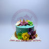 One-tier tropical anniversary cake with ombre blue-green buttercream, vibrant sugar paste hibiscus flowers, sand decor, and 'Happy 32nd Anniversary USC CHEC' text.