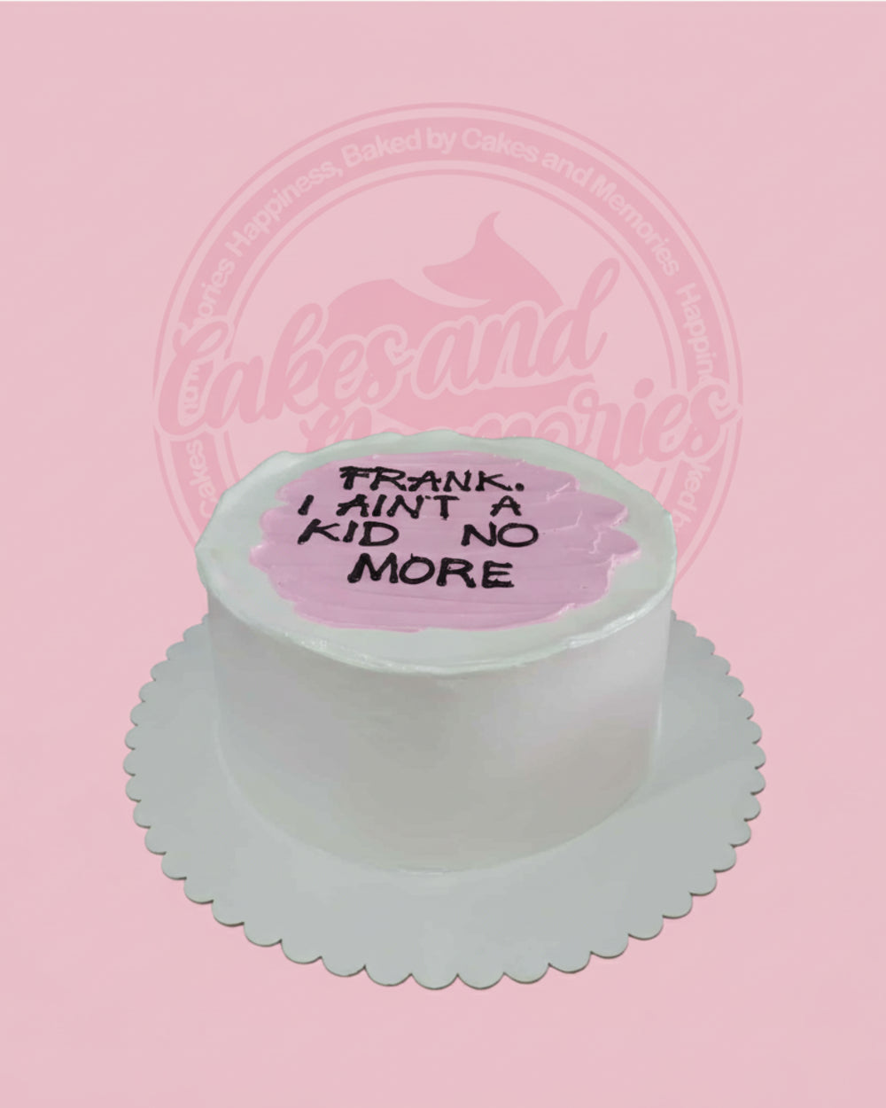 Round one-tier custom message cake with white buttercream and pink top, featuring 'FRANK, I AIN'T A KID NO MORE' in black.