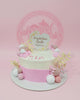 One-tier baptism cake with white and pink buttercream, adorned with edible spheres, meringues, foliage, and a 'Krystalaine Noelle Baptism' topper.
