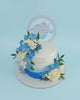 Custom buttercream cake with white to blue ombre icing, adorned with white roses and blue sugar flowers and green leaves.