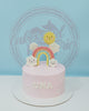 One-tier pink buttercream birthday cake with smiling rainbow, sun, and clouds, personalized with 