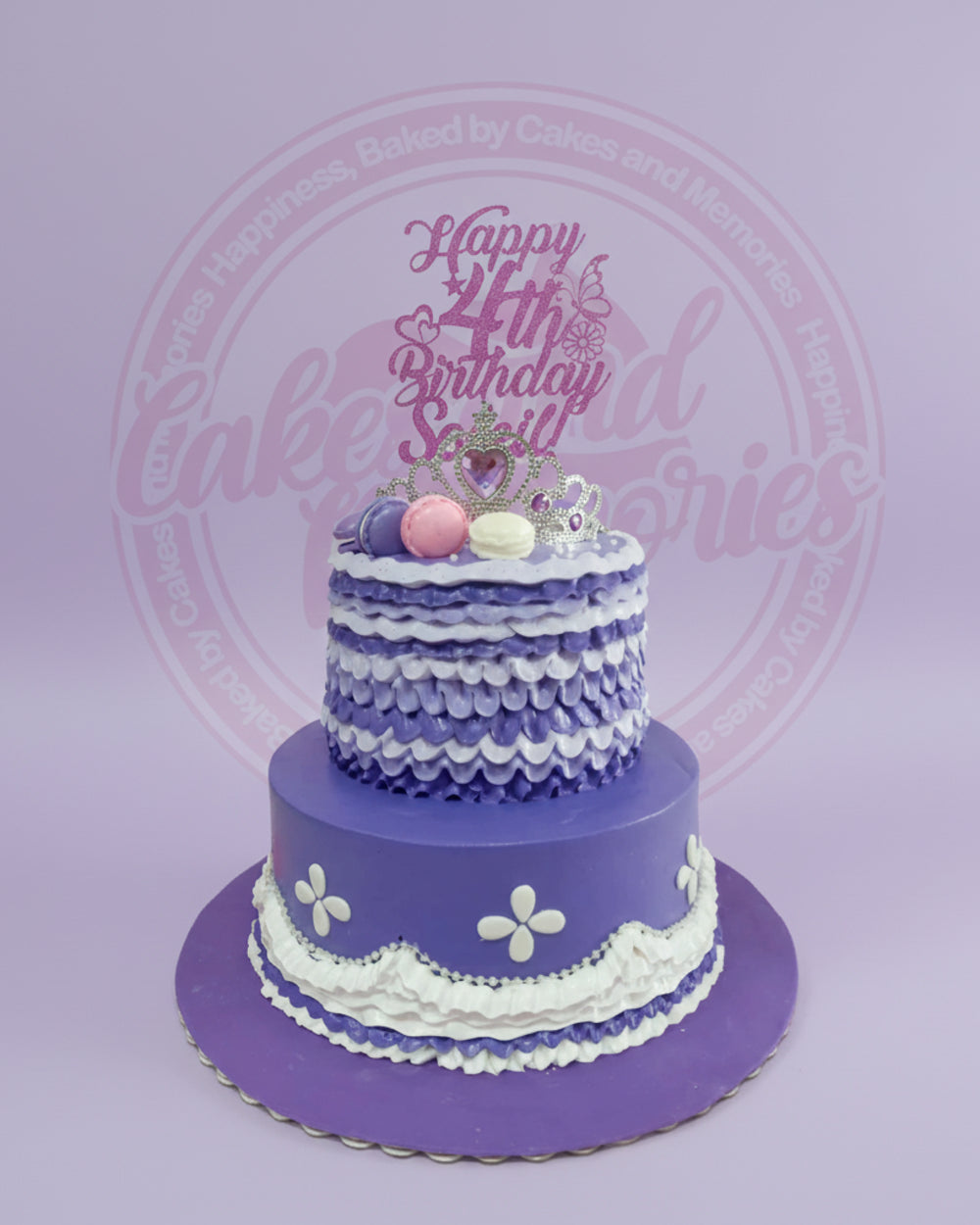Two-tier custom birthday cake with 'Happy 4th Birthday Sairil' glitter topper, silver crown, and macarons on purple and white buttercream.