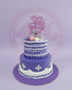 Two-tier custom birthday cake with 'Happy 4th Birthday Sairil' glitter topper, silver crown, and macarons on purple and white buttercream.