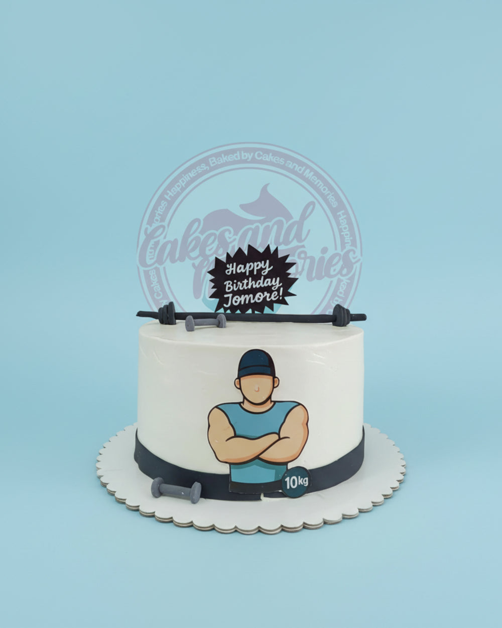 One-tier custom birthday cake with a gym theme, featuring a muscular man print, barbell, dumbbells, and 'Happy Birthday Jomore!' topper in white, blue, and grey.