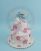 Two-tier pink birthday cake adorned with delicate white butterflies, pink fondant flowers, and shimmering pearls, topped with 'Happy Birthday'.