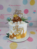 Custom 50th birthday cake with white and gold icing, sugar flowers, macarons, and 'Mona @ 50' text.