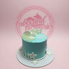 Custom under the sea birthday cake with aqua blue buttercream, white shells, starfish, and 'Happy birthday JULIE MARLE!'