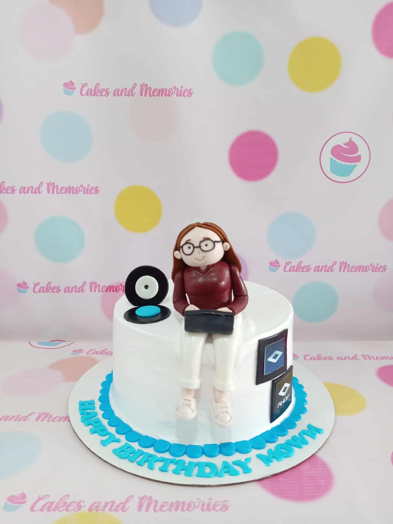 One-tier fondant birthday cake for Mom, featuring a woman with laptop, record player, and app icons in white, blue, and black.