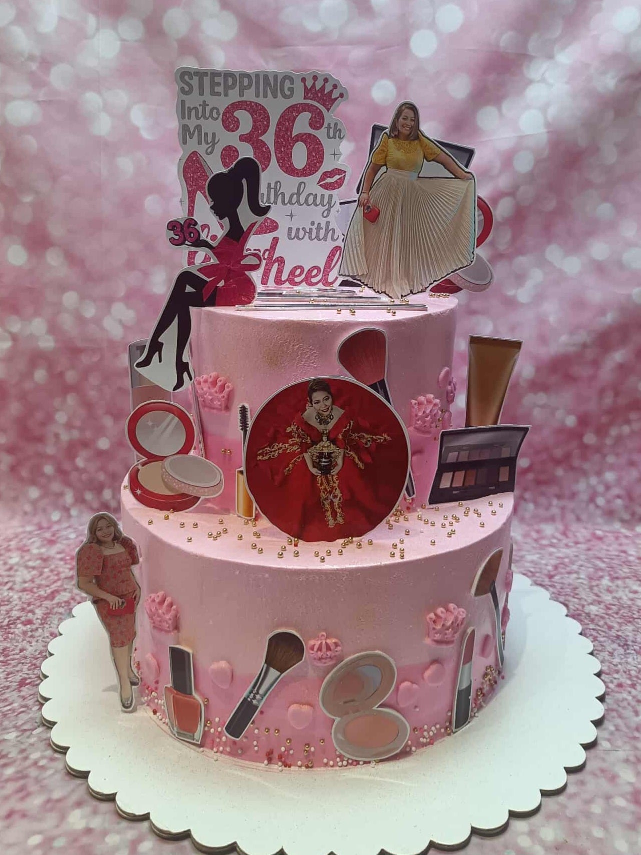Two-tier custom 36th birthday cake with pink buttercream, "Stepping Into My 36th Birthday" topper, photos, and makeup prints.