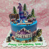 This Fortnite Cake features a stunning blue and purple ombre design, adorned with a playful Llama, trees, chests, grenades, bullets, and rocks, perfect for celebrating Gab's 11th birthday. The cake is topped with vibrant printout toppers inspired by video games on PS5 and Xbox, showcasing a single tier for a unique party centerpiece.