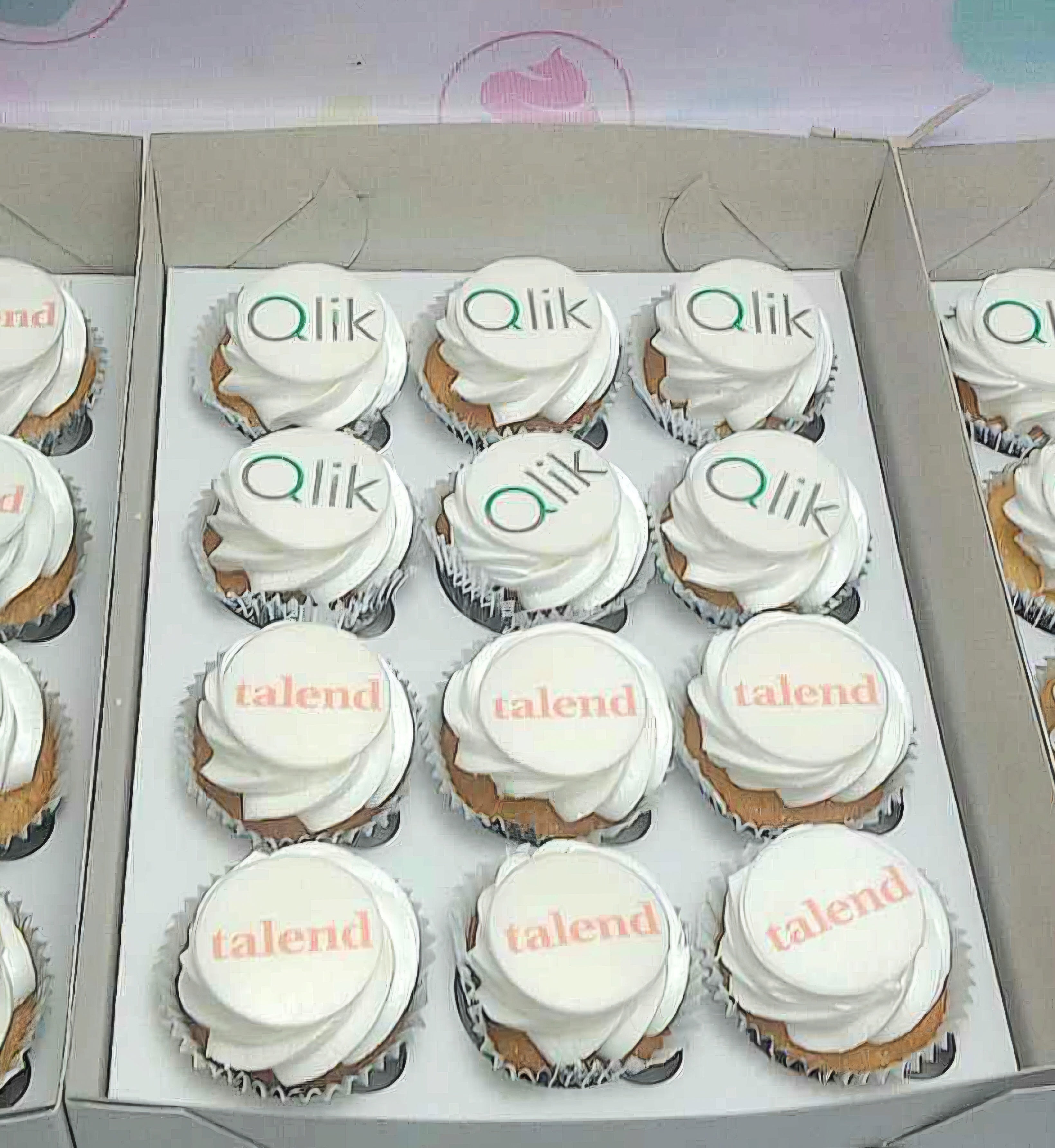 A collection of elegant vanilla cupcakes adorned with smooth white icing, featuring custom edible photo toppers for Qlik, Talend, and BPO themes, perfect for business office events and call centers. Ideal for corporate giveaway occasions.