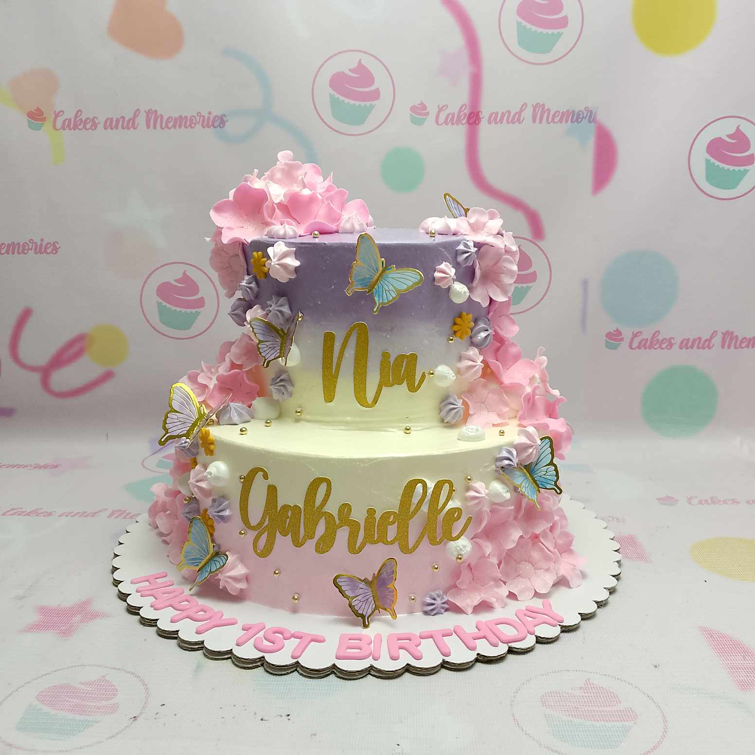 This enchanting Butterflies Cake features a stunning purple and cream color palette, adorned with delicate pink flowers and shimmering gold glitter name designs. With two elegant layers and delightful butterfly toppers, it's the perfect centerpiece for any birthday celebration.