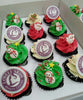 A festive display of Christmas cupcakes features red, green, and white swirls topped with charming Santa, snowman, gingerbread man, and Christmas tree decorations. Each cupcake is adorned with an edible photo logo for Loveli Skin Beauty Centre, complemented by printout toppers and a star motif.