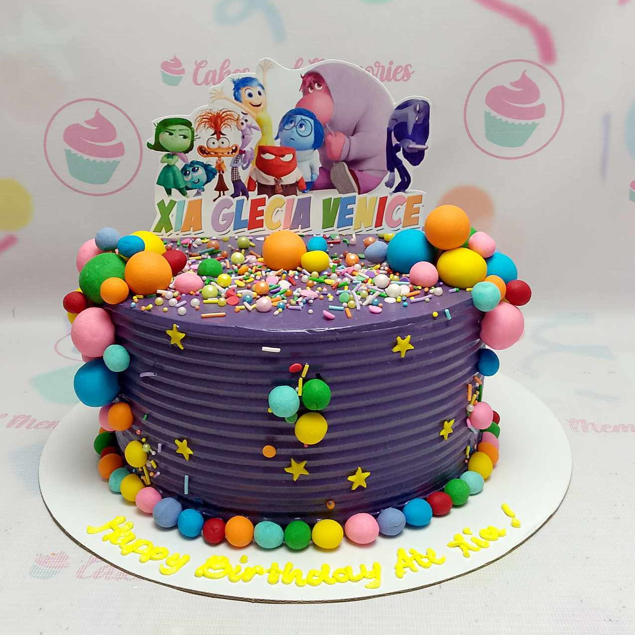 This vibrant Inside Out Cake features stunning violet hues and playful rainbow toppers inspired by the beloved Pixar movie, showcasing emotions like joy, sadness, anger, and anxiety. Perfect for any celebration, this single-layer, one-tier cake is a colorful tribute to the magic of emotions.