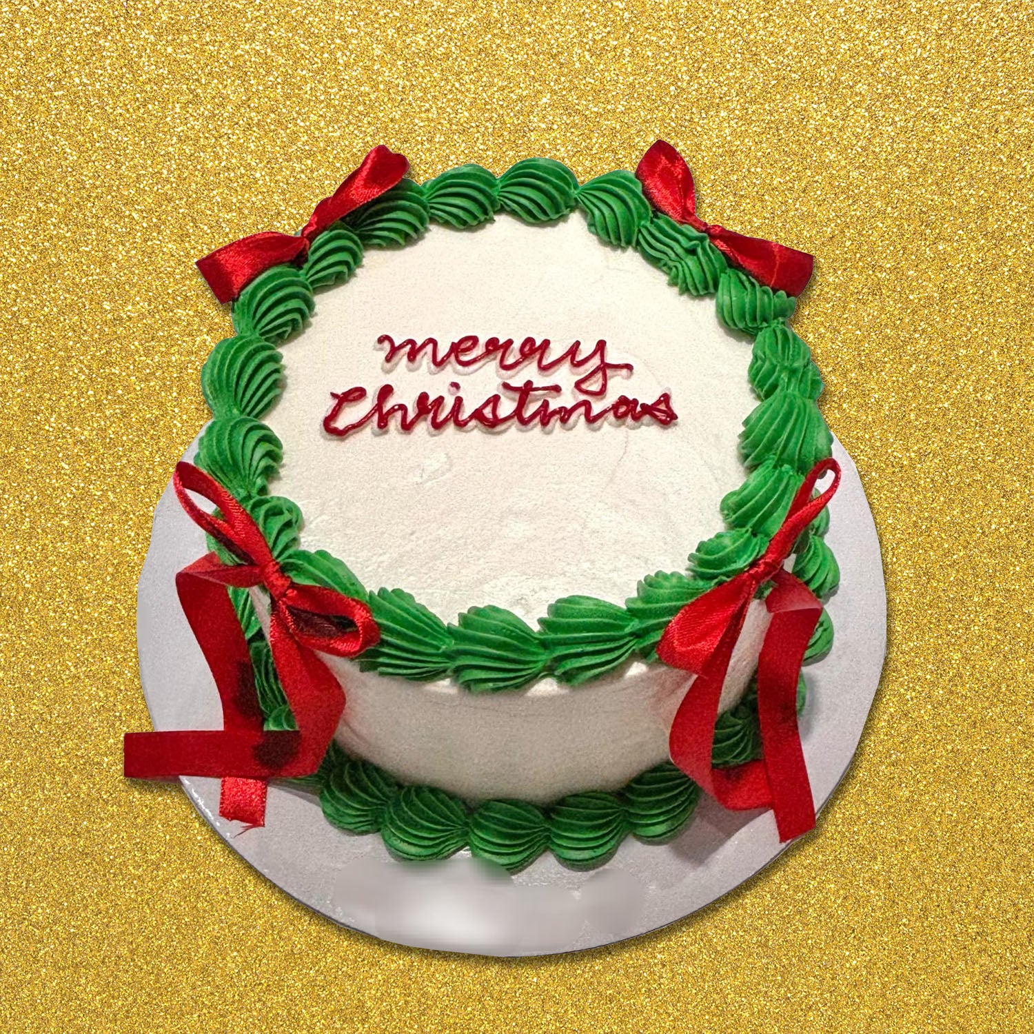 This elegant Christmas cake features a smooth white surface adorned with a festive wreath design, red ribbon bows, and green swirls, perfect for any Christmas party or celebration. The single tier showcases a cheerful "Merry Christmas" message, adding to the holiday spirit.