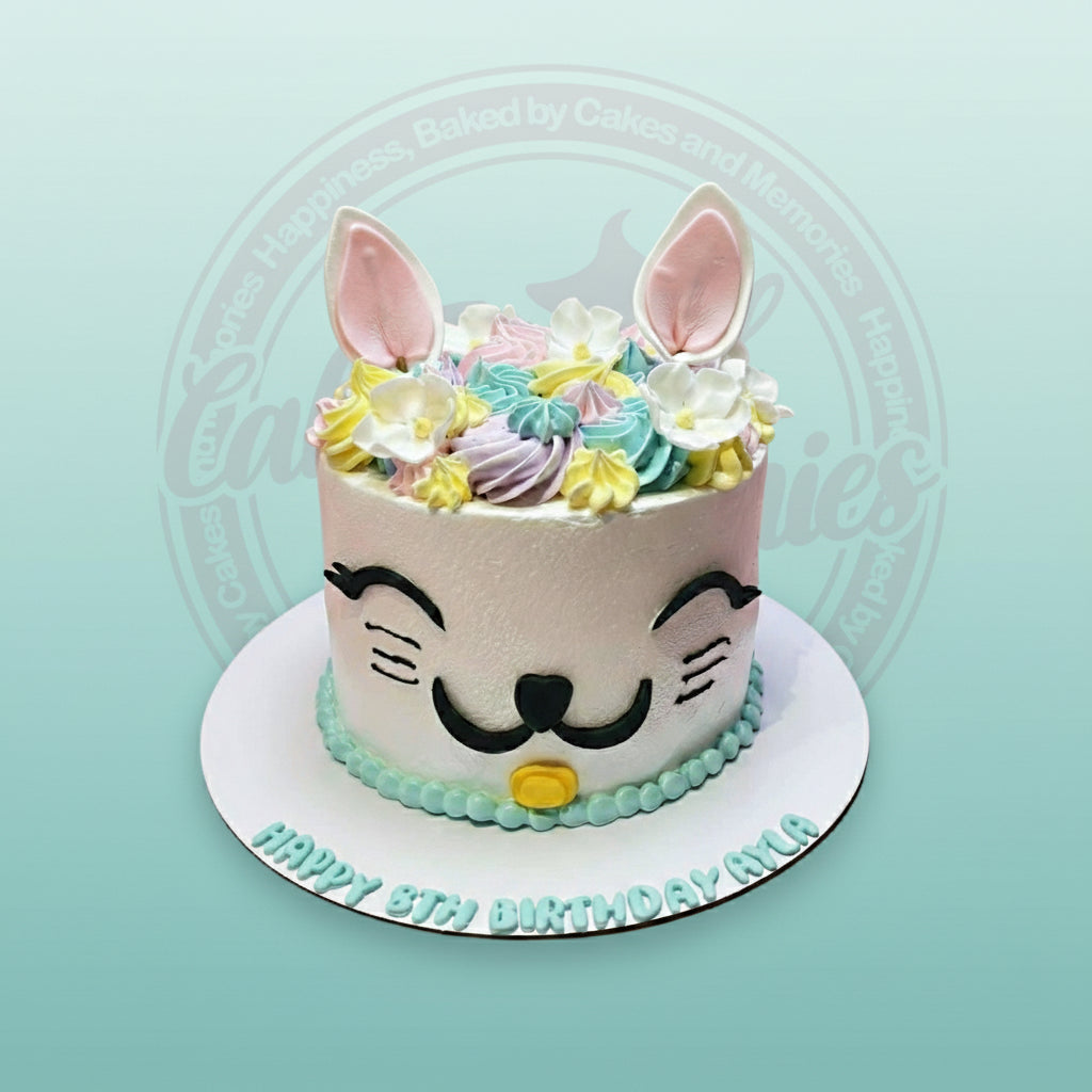 Custom birthday cake with a cute white cat face, pastel buttercream swirls, pink ears, and "HAPPY 8TH BIRTHDAY AYLA" text.