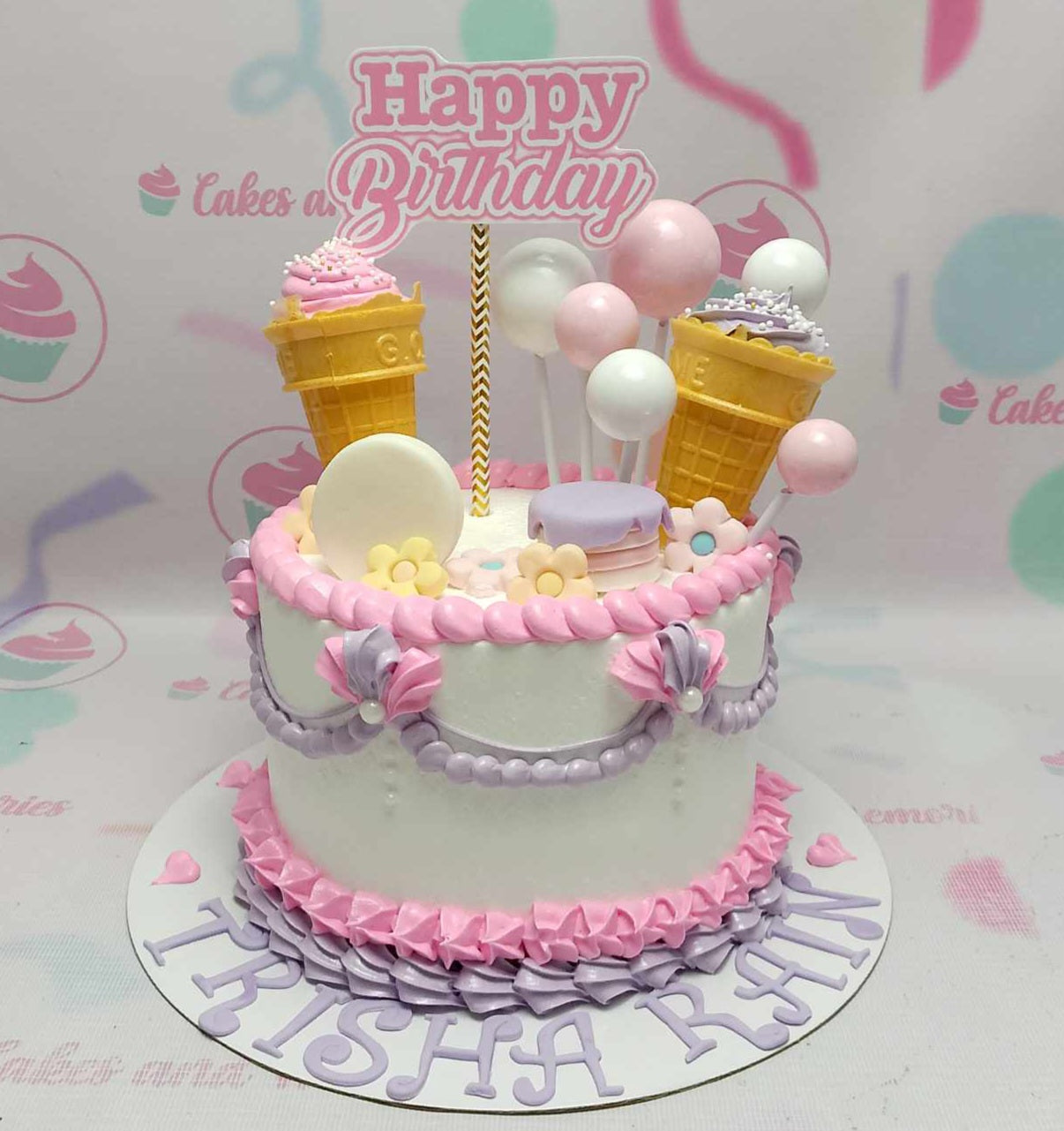 A stunning Candyland Cake showcasing shades of pink and purple, adorned with ice cream cones, lollipops, flowers, hearts, and macarons. This one-tier, vintage cake design features delightful printout toppers and an array of colorful candies.