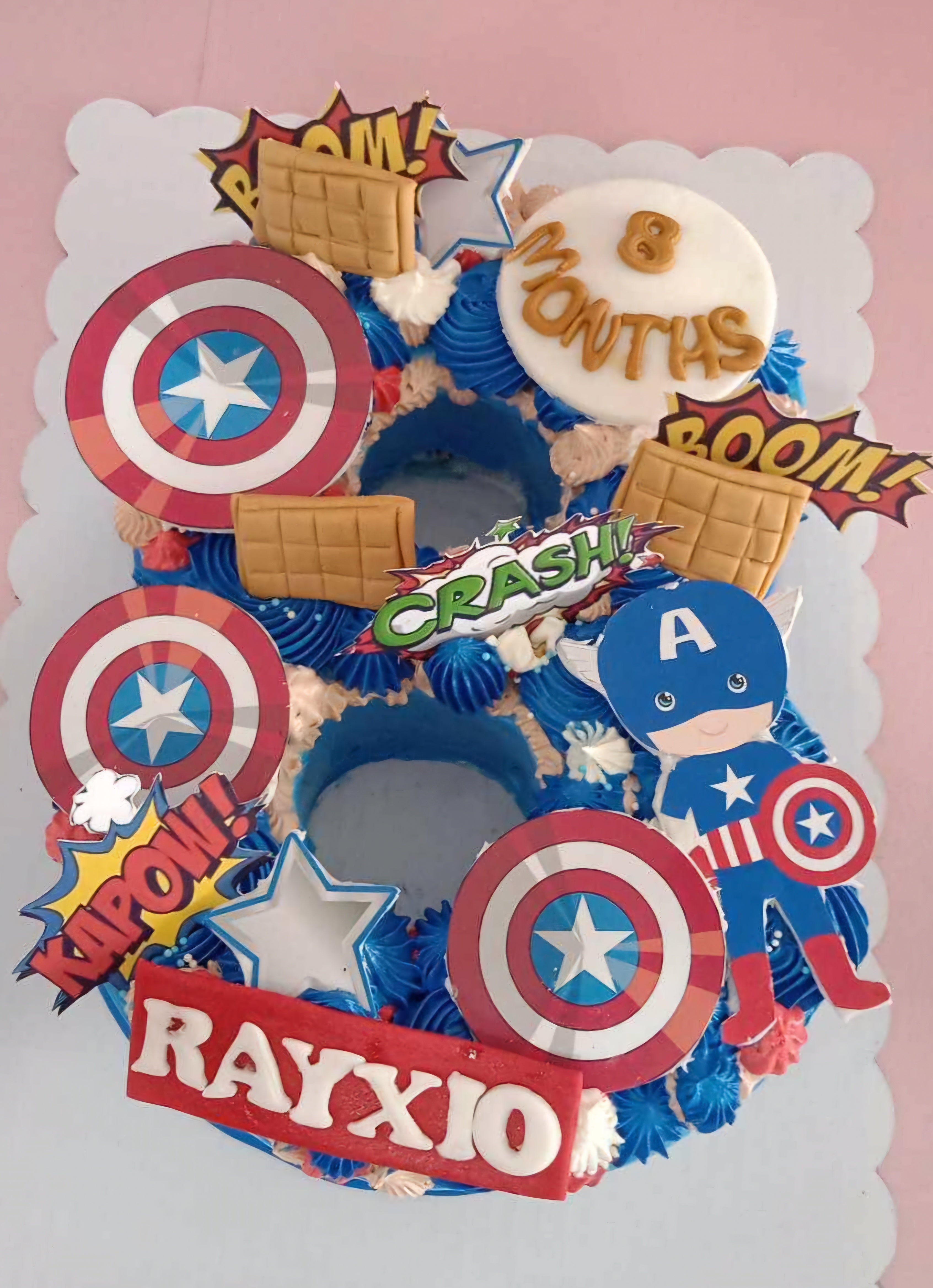 This custom Avengers cake features a striking blue design with Captain America's iconic shield at the center, surrounded by comic-style “kapow” and “boom!” graphics. Perfectly rectangular for superhero fans, it's a fun centerpiece for any kids' celebration.