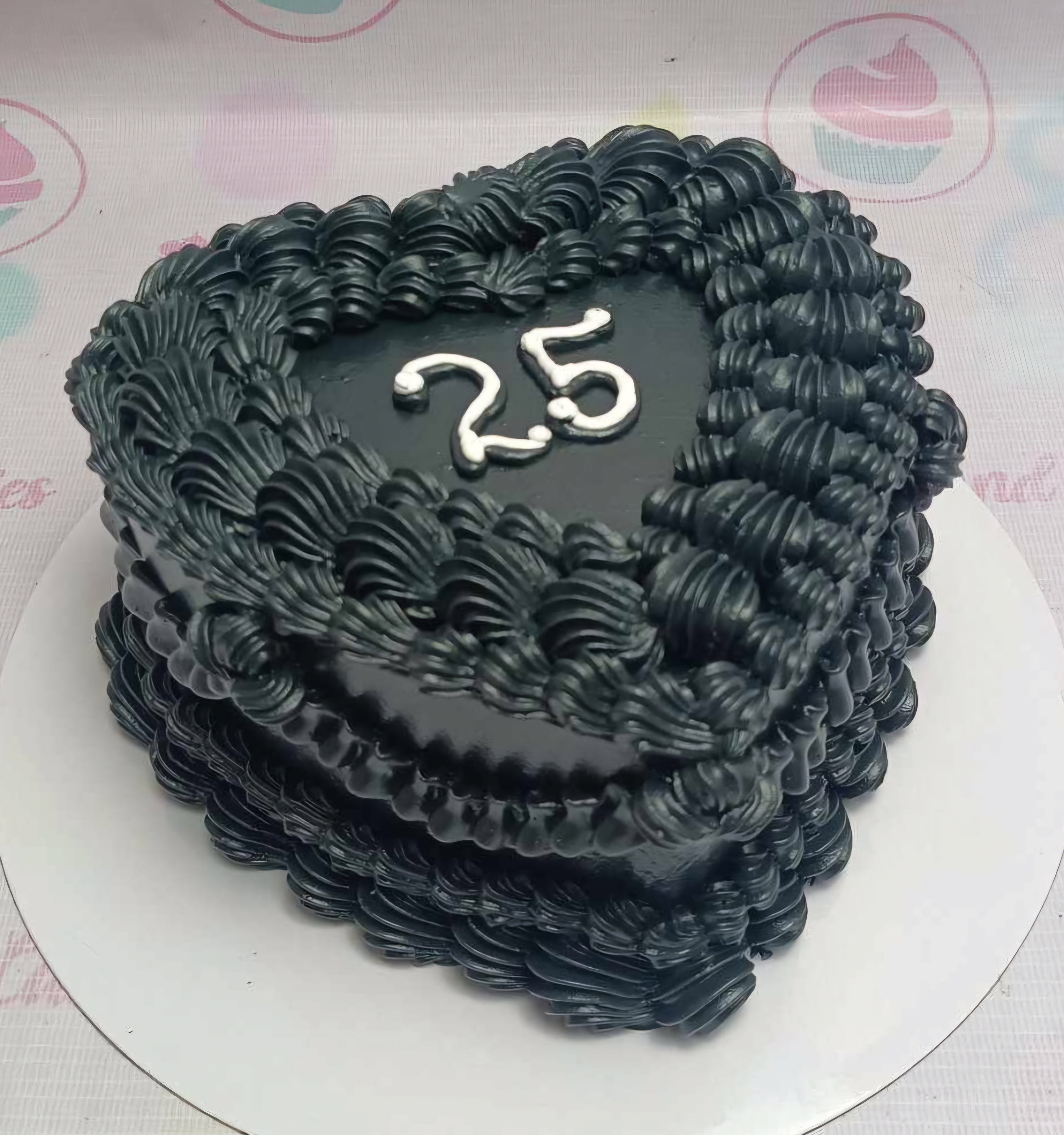 A beautiful vintage black heart-shaped cake, designed for a 25th birthday celebration, features elegant swirls perfect for her anniversary. This classic 1-tier cake embodies the spirit of a sweetheart's special day.