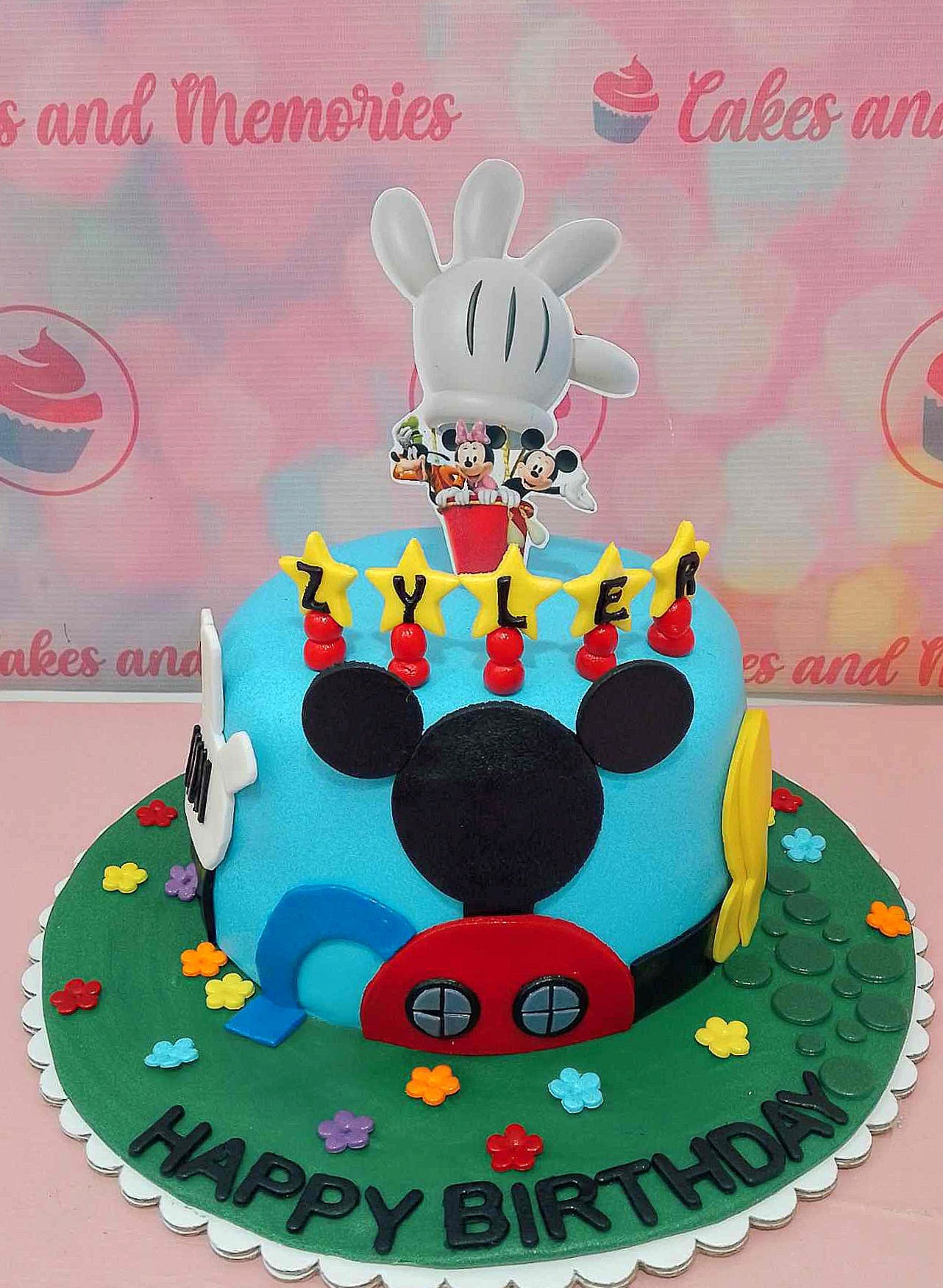 This delightful Mickey Mouse cake features blue fondant icing and showcases beloved characters like Mickey, Minnie, Pluto, and Goofy, adorned with stars and flowers. Ideal for any Disney fan, it includes cheerful printout toppers and is designed as a single-layer, one-tier masterpiece.