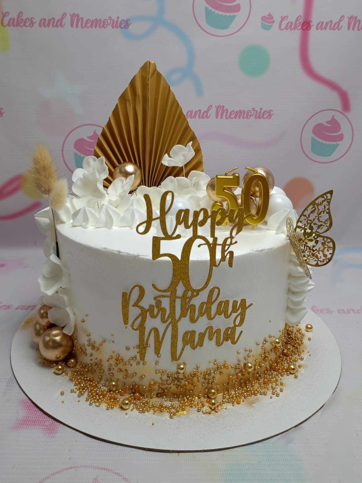 This stunning Fifty Cake features a sleek white design adorned with elegant gold accents, including a gold paper leaf fan and a delicate gold butterfly. Perfect for celebrating milestone birthdays, it is customizable for seniors turning 50, 60, 70, or 80, and comes with themed printout toppers.