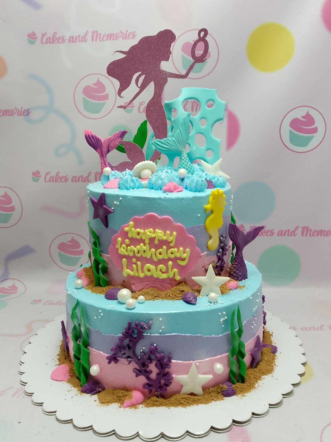 This enchanting two-tier Mermaid Cake captures the essence of the ocean with its teal, purple, pink, and blue palette, adorned with seashells, sea-horses, and shimmering pink glitters. Perfect for an 8th birthday celebration, it features a stunning mermaid tail that invites little ones to dive into an under-the-sea adventure.