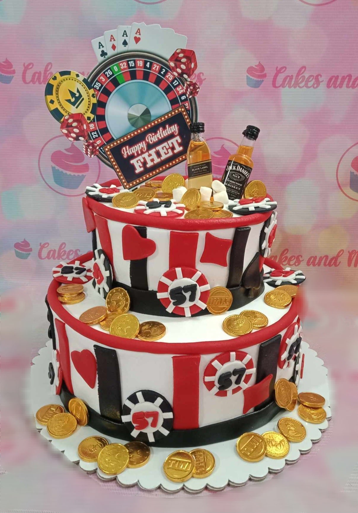 This stunning two-tier Casino Cake features a sleek white, red, and black design, adorned with roulette and playing card toppers, Jack Daniels accents, and an array of casino chips and gold coins. Perfect for any online gambling enthusiast, it captures the essence of Las Vegas with its full house and royal flush themes.