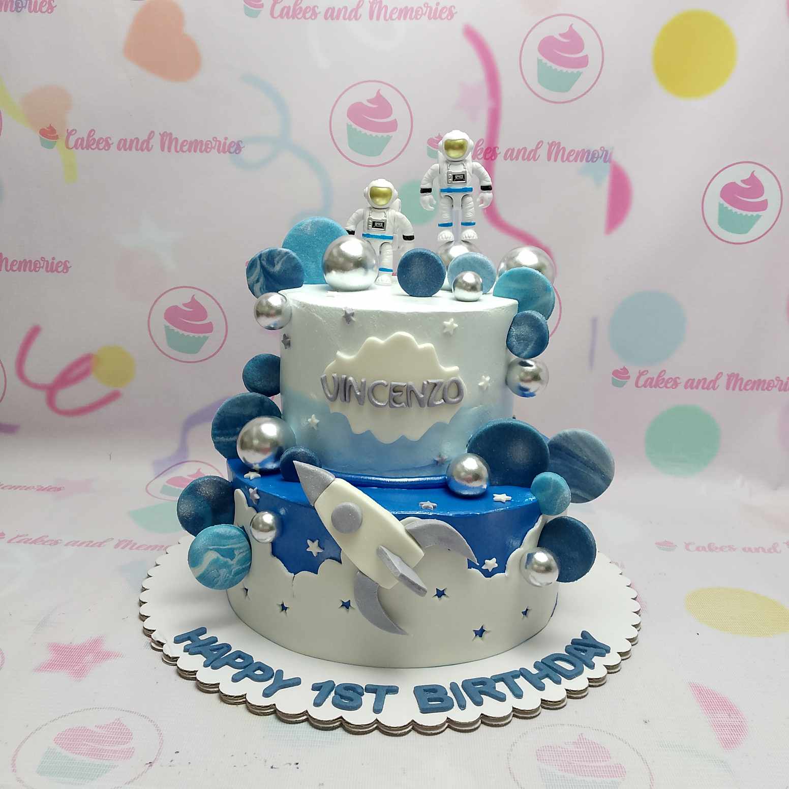 Celebrate your child's special day with our enchanting Space Cake, featuring two delicious layers adorned in blue and white with silver accents. Decorated with a whimsical rocketship and playful astronauts, this customized 2-tier cake is perfect for any young space explorer dreaming of the galaxy!