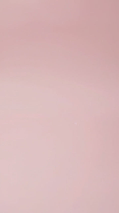 A single-tier white cake with red textured frosting, decorated with delicate paper butterflies on a soft pink background.