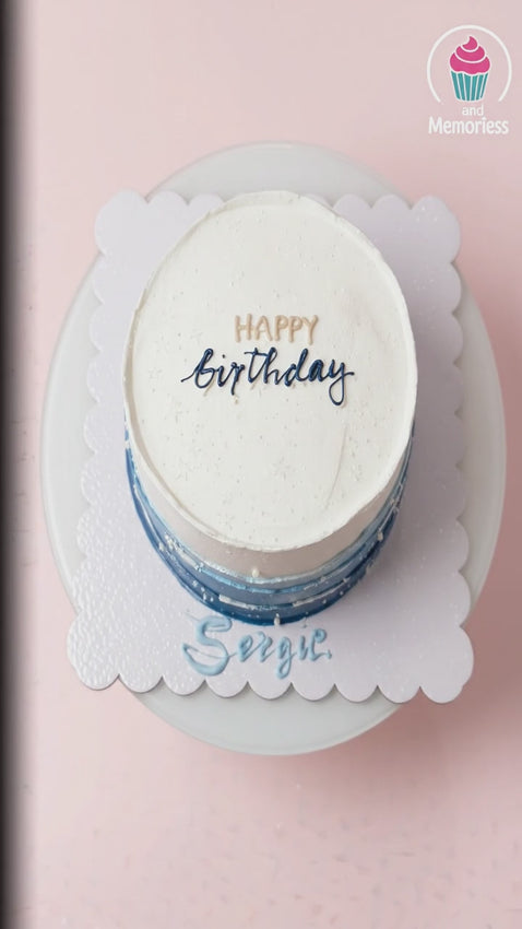 A 1-tier 8-inch round cake with a white to dark blue ombre design, decorated with white pearl dragees and custom birthday text.