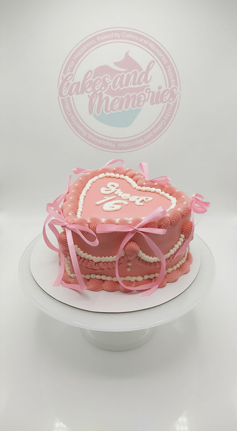 Pink heart-shaped Sweet 16 cake with vintage piping and satin ribbon bows