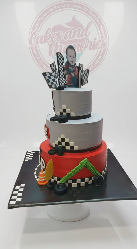 3-tier F1 racing 1st birthday cake with red and gray tiers, checkered flags, and race car topper