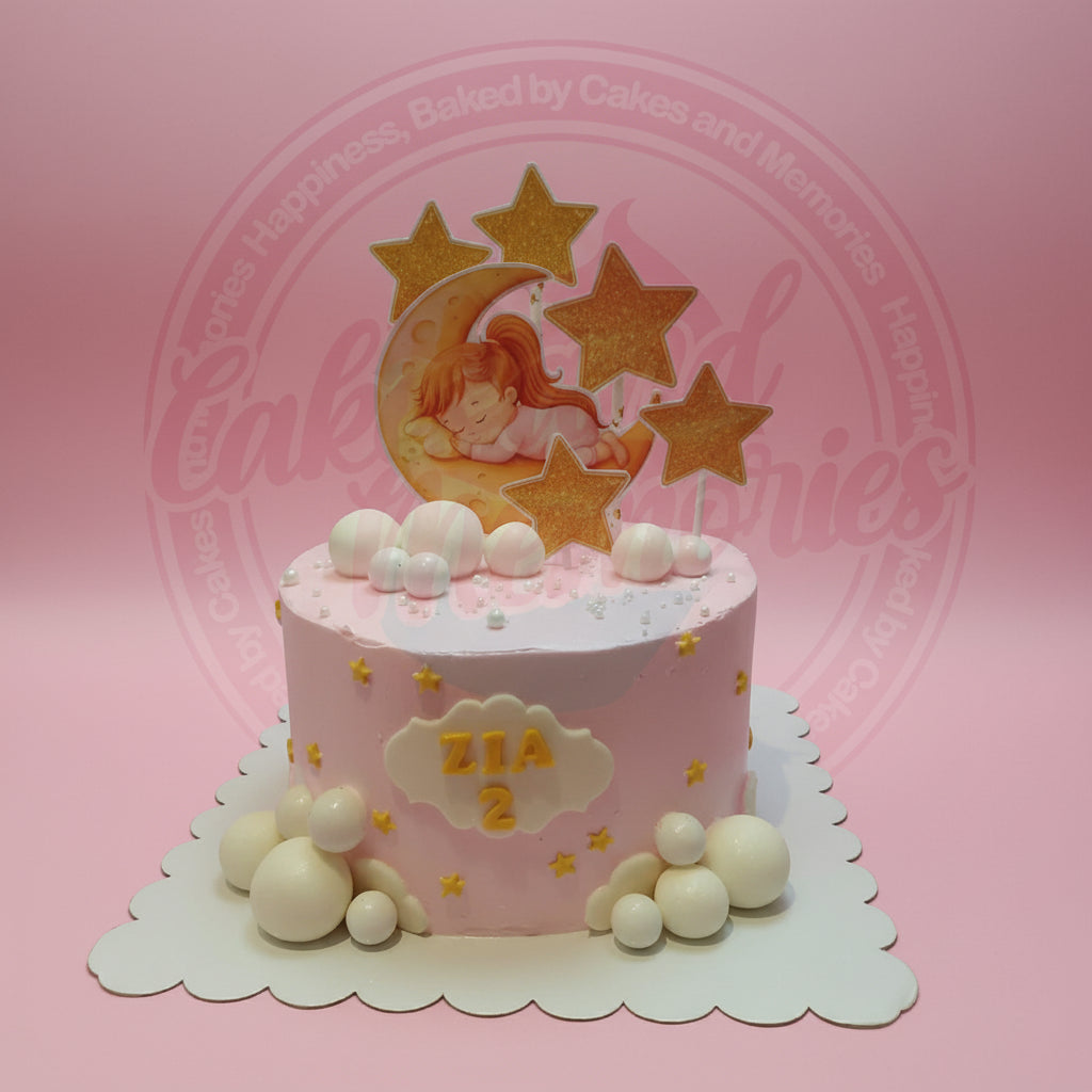 One-tier pink custom birthday cake with a sleeping girl on moon topper, golden stars, white and pink spheres, and a "ZIA 2" plaque.