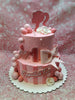 Two-tier pink Barbie 1st birthday cake with a glittery silhouette, number one, name Czyailah Fae, and pink stripes.