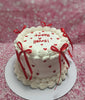 Anniversary cake with white buttercream, red heart sprinkles, 'Happy V Years!' text, and red ribbon bows.