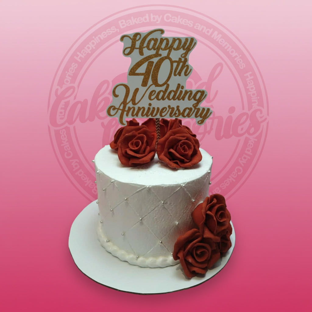 One-tier 40th Wedding Anniversary cake with white buttercream, quilted pattern, silver pearls, red roses, and gold glitter topper.